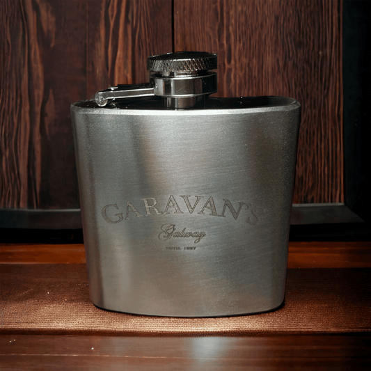 A silver hip flask with a cap, engraved with 'Garavan's Bar' on the front